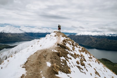 The man standing on the snow-capped mountains during the day
